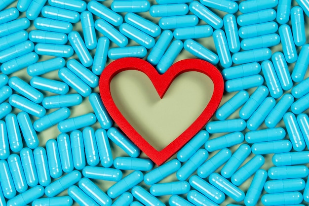 Foto forma de corazón y cápsulas azules importancia del tratamiento farmacológico