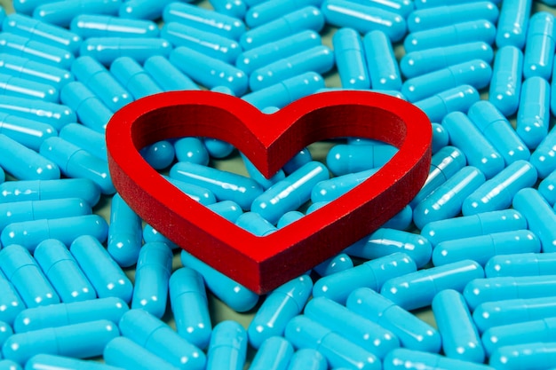 forma de corazón y cápsulas azules Importancia del tratamiento con medicamentos