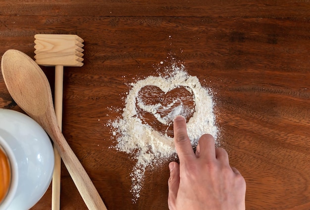 Forma de corazón con harina sobre fondo de encimera de madera rústica