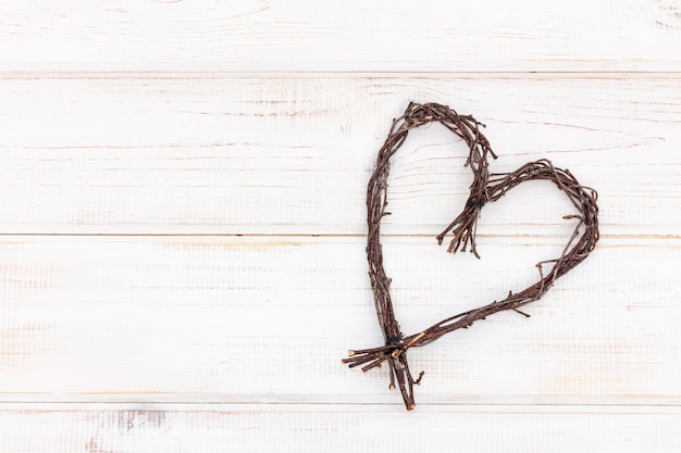 Foto en forma de corazón hecha de ramitas - símbolo de madera del amor sobre un fondo blanco.