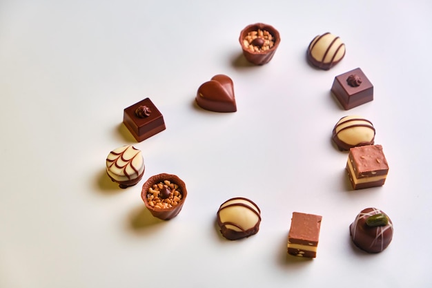 Forma de corazón hecha con varios tipos de trufas de chocolate sobre una mesa blanca