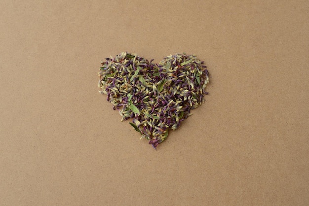 Foto en forma de corazón de hierba verde seca, hojas y flores de trébol morado. tarjeta de san valentín creativa