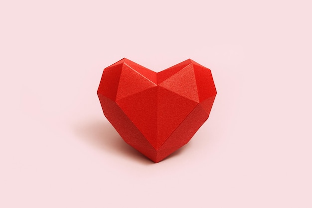 Forma de corazón de papel poligonal rojo en fondo de color crema Fondo de vacaciones con espacio de copia para el Día de San Valentín Concepto de amor de color sencillo Estilo minimalista