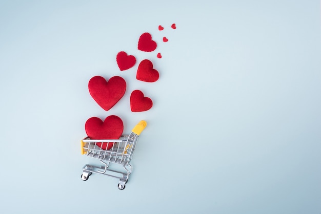 En forma de corazón rojo con carrito de compras sobre fondo azul para la boda de amor y el día de San Valentín.