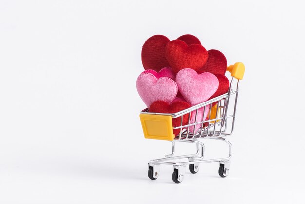 En forma de corazón rojo y rosa en el carrito de compras para bodas de amor y día de San Valentín.