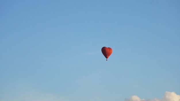 Forma de balão de ar quente de um coração no balão vermelho do aeróstato de céu azul