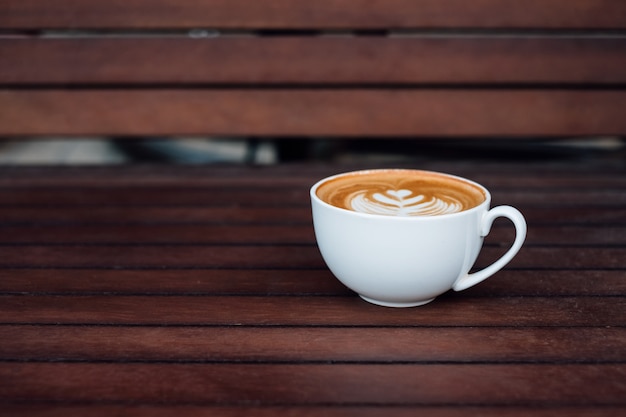 Forma de coração de xícara de café com leite quente colocar na mesa de madeira