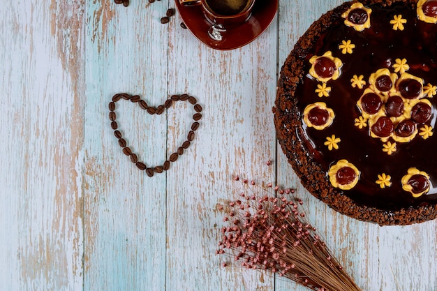 Forma de coração feita de grãos de café com bolo de chocolate e cereja
