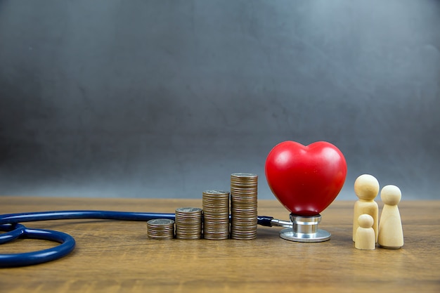 Forma de coração vermelho e Moedas são empilhadas em forma de gráfico. E estetoscópio médico O conceito de um exame físico e seguro de saúde.