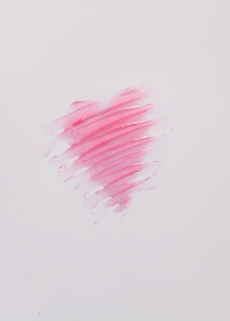 Foto forma desenhada à mão do coração. amostra de brilho labial rosa em um fundo branco.