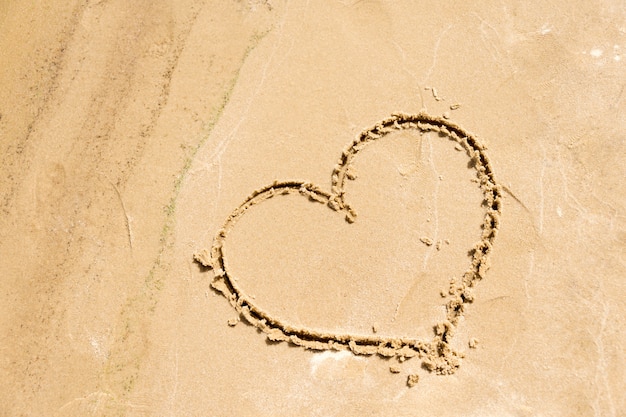Forma do coração desenhada na areia na praia