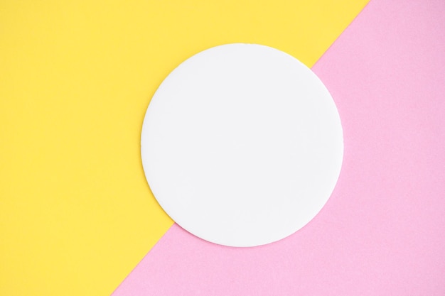 Forma geométrica redonda vazia em cor branca sobre fundo de papel colorido rosa e amarelo