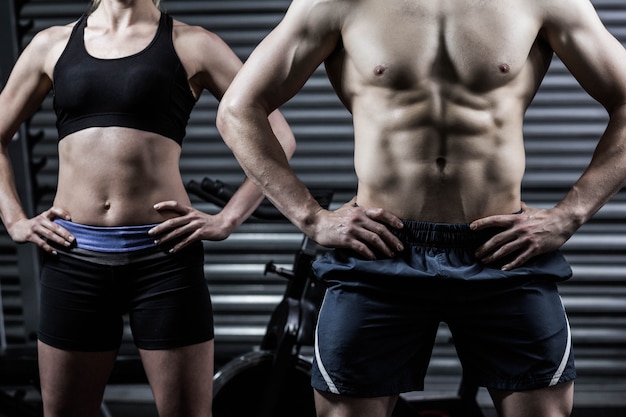 Forma pareja con las manos en las caderas en el gimnasio