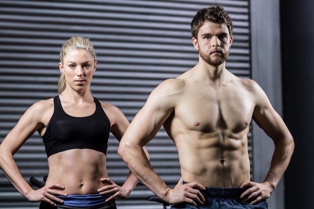 Forma pareja con las manos en las caderas en el gimnasio