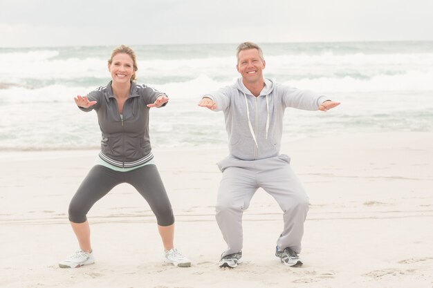 Forma pareja sonriendo a la cámara en la playa