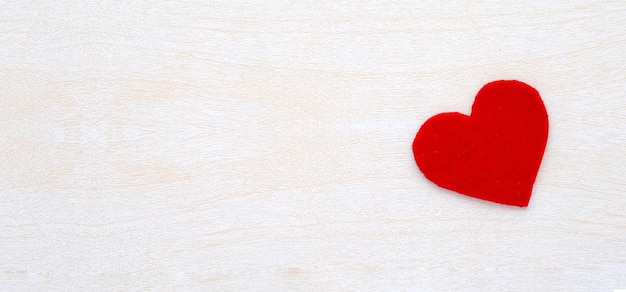 Forma vermelha do coração do tecido no fundo branco da madeira. Fundo do dia dos Namorados.