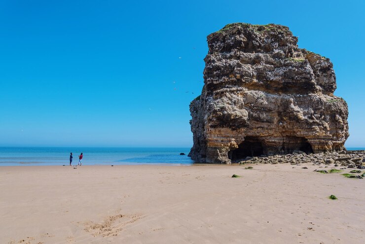 Foto formação rochosa na praia contra o céu azul claro