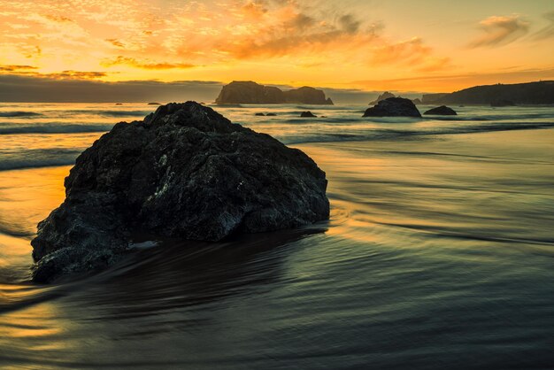 Foto formação rochosa no mar contra o céu durante o pôr-do-sol