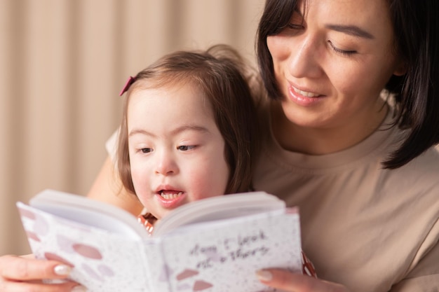 Foto formación de las habilidades de una niña con síndrome de down con su madre y un libro en casa leído