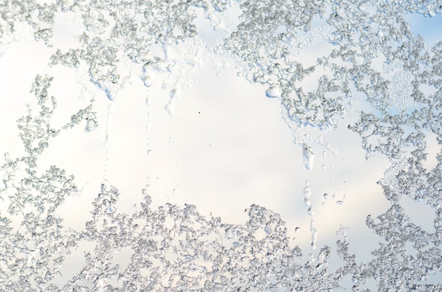 Formación de hielo en el cristal de la ventana, escarcha sobre fondo de cielo azul en invierno