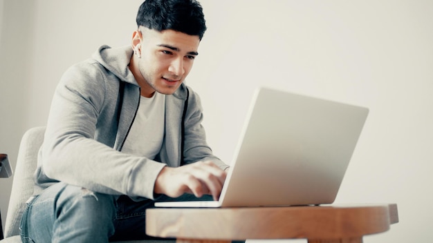 Formación en línea El programador está sentado en el sofá de casa frente a la computadora