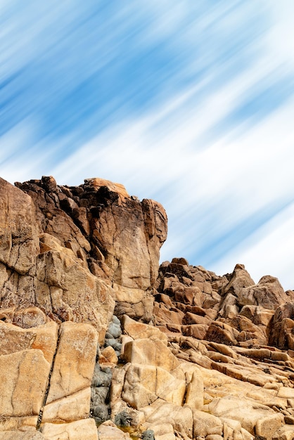 Formación rocosa contra el cielo en el área de Sillon de Talbert en Gran Bretaña larga exposición nubes en movimiento