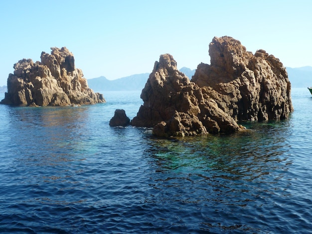 Formación rocosa en el mar contra un cielo azul claro