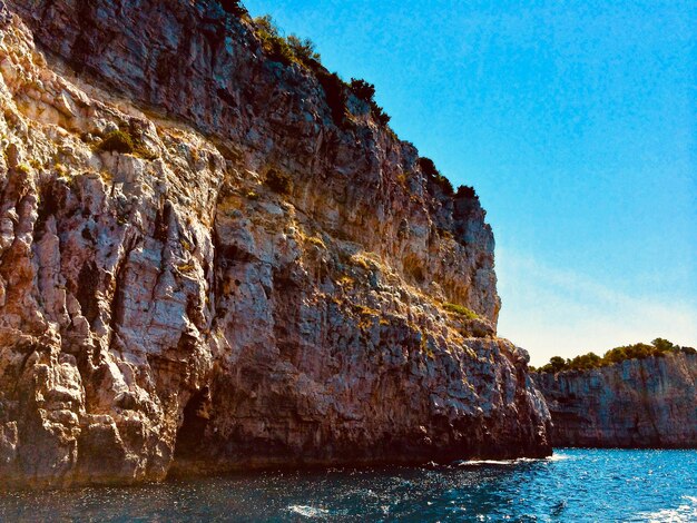 Foto formaciones rocosas por el mar contra un cielo azul claro