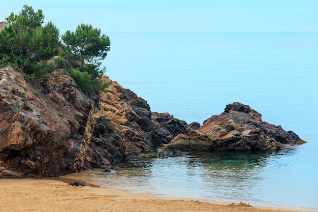 Formações rochosas com pinheiros na praia arenosa de La Fosca, Palamos, Girona, Costa Brava, Espanha.