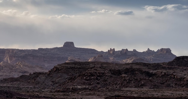 Formações rochosas de montanha áspera no deserto com nuvens dramáticas ao pôr do sol