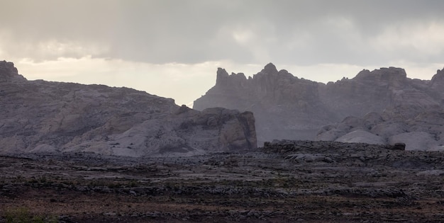 Formações rochosas de montanha áspera no deserto com nuvens dramáticas ao pôr do sol