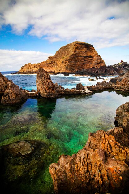 Foto formações rochosas no mar contra o céu nublado