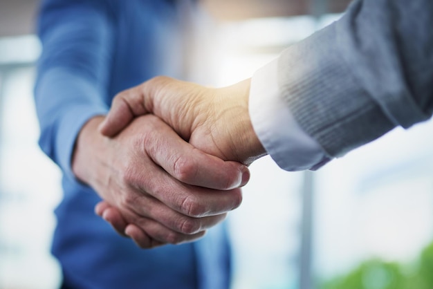 Formando una nueva fusión Captura de pantalla de dos hombres de negocios irreconocibles dándose la mano en una oficina