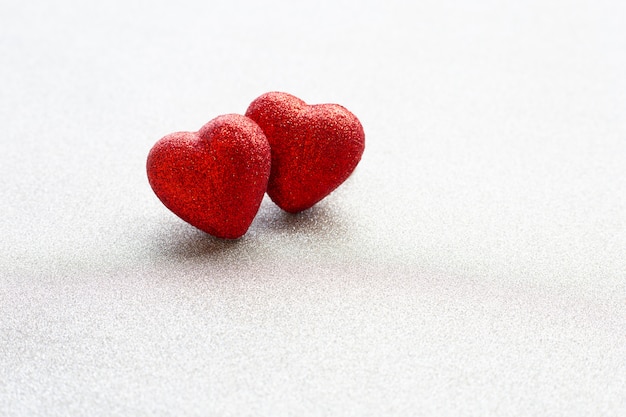 Las formas de corazón rojo sobre fondo de papel glitter plateado en concepto de amor para el día de San Valentín