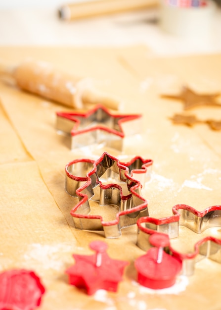 Formas e massa de pão de gengibre vermelho em papel manteiga. Preparando-se para o Natal.