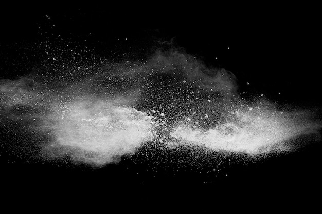 Formas estranhas da nuvem branca da explosão do pó contra o fundo preto. Respingo das partículas de poeira branca.