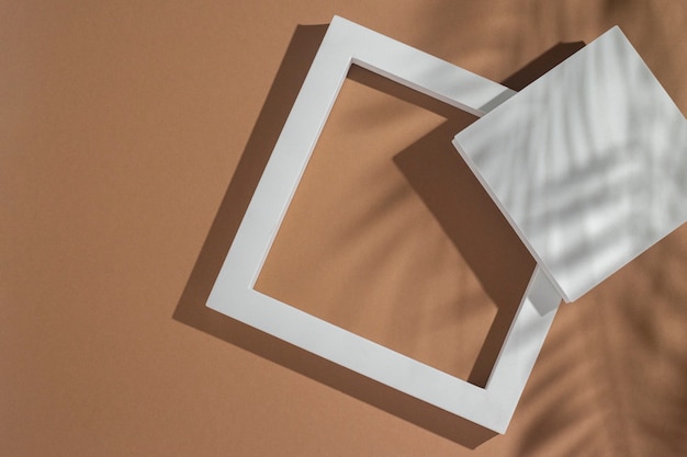 formas geométricas de pódios de apresentação branca sob a sombra de folhas de palmeira em um fundo marrom