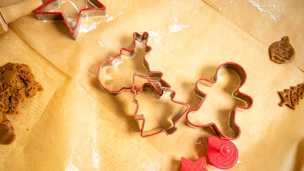 Formas de pan de jengibre rojo y masa sobre papel de hornear marrón. Preparándose para la Navidad.