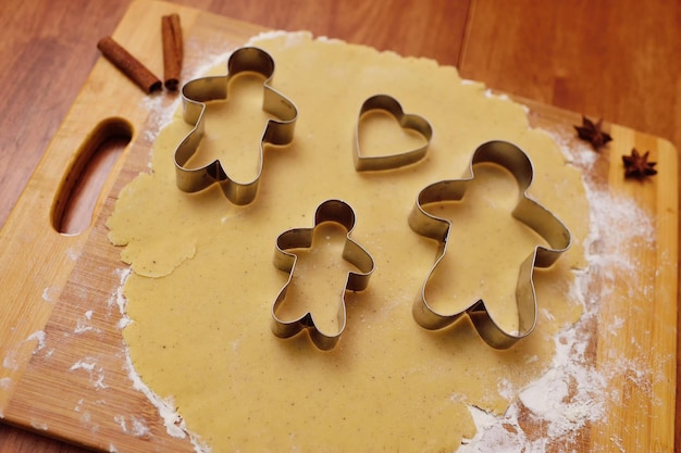 Formen zum Backen von Lebkuchen in Form eines Mannes und eines Herzens auf dem Hintergrund eines Nudelholzes und einer gerollten Teignahaufnahme