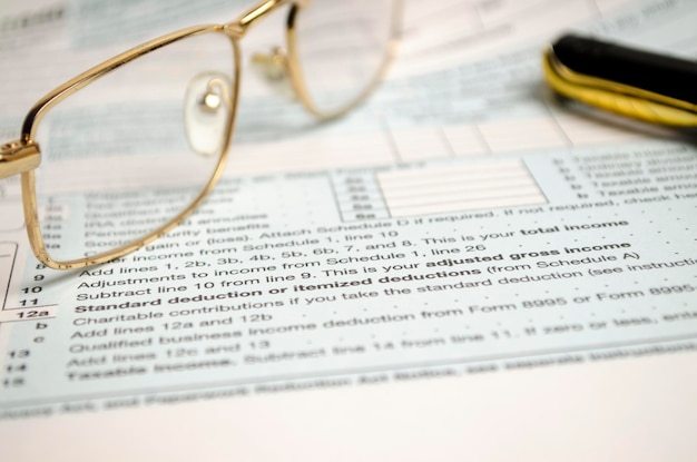Formulário de declaração de imposto com óculos e caneta em fundo branco