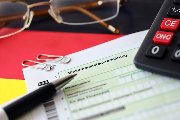Formulário de declaração de imposto de renda alemão com caneta e notas de euro europeias está na bandeira de perto Contribuintes na Alemanha usando moeda euro para pagar impostos