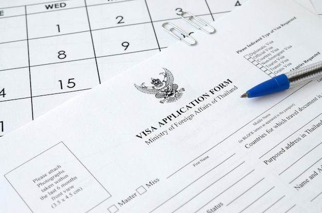 Formulário de pedido de visto de Tailândia e caneta azul na página de calendário de papel