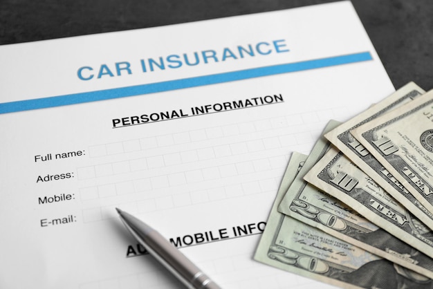 Formulario de seguro de automóvil y dinero en la mesa