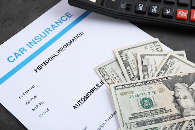 Formulario de seguro de automóvil y dinero en la mesa