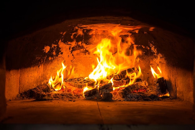 Forno de pizza italiano tradicional queima de madeira e chamas na lareira