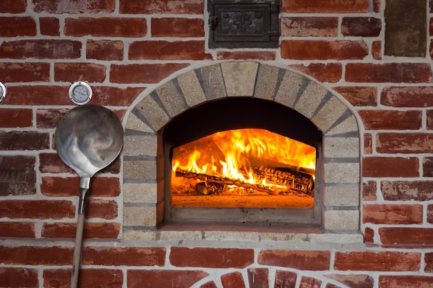 Forno de pizza italiano tradicional queima de madeira e chamas na lareira