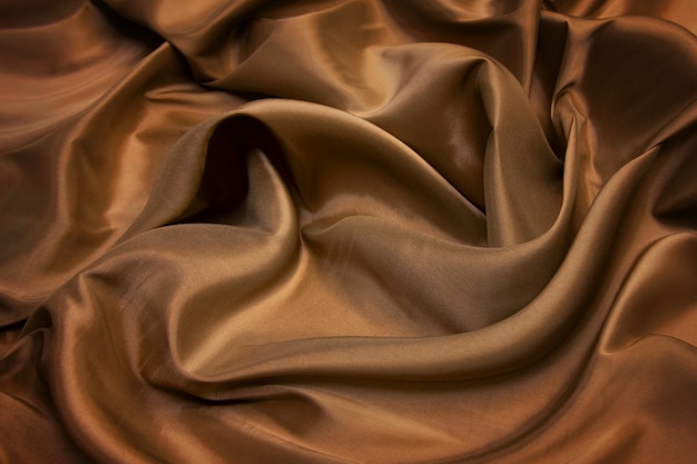 Forro de seda castanho. Closeup de linhas em tecido de seda marrom. Fundo marrom com sombras e linhas suaves.