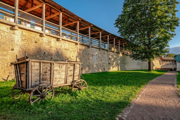 Fortaleza de Izborsk e um antigo carrinho de aldeia tradicional em uma ensolarada noite de verão região de Izborsk Pskov