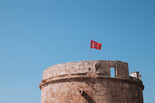 Fortaleza de piedra y bandera turca en el casco antiguo de Kaleici. Torre Hidirlik en Antalya, Turquía.