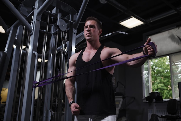 Forte atleta masculino musculoso treinando com banda de resistência